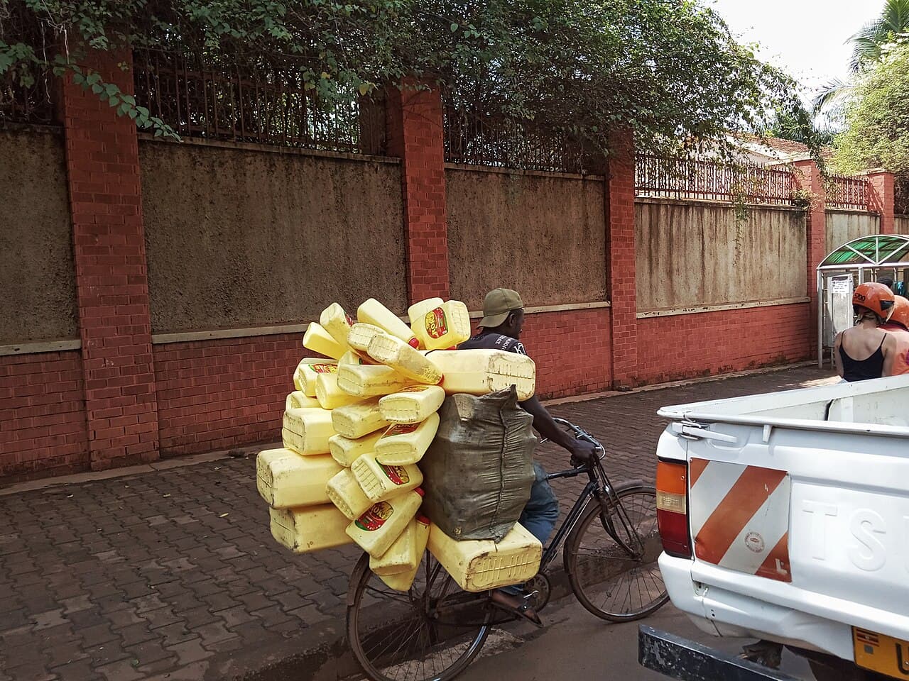 A boda boda rider in Kampala transporting a large load of jerry cans