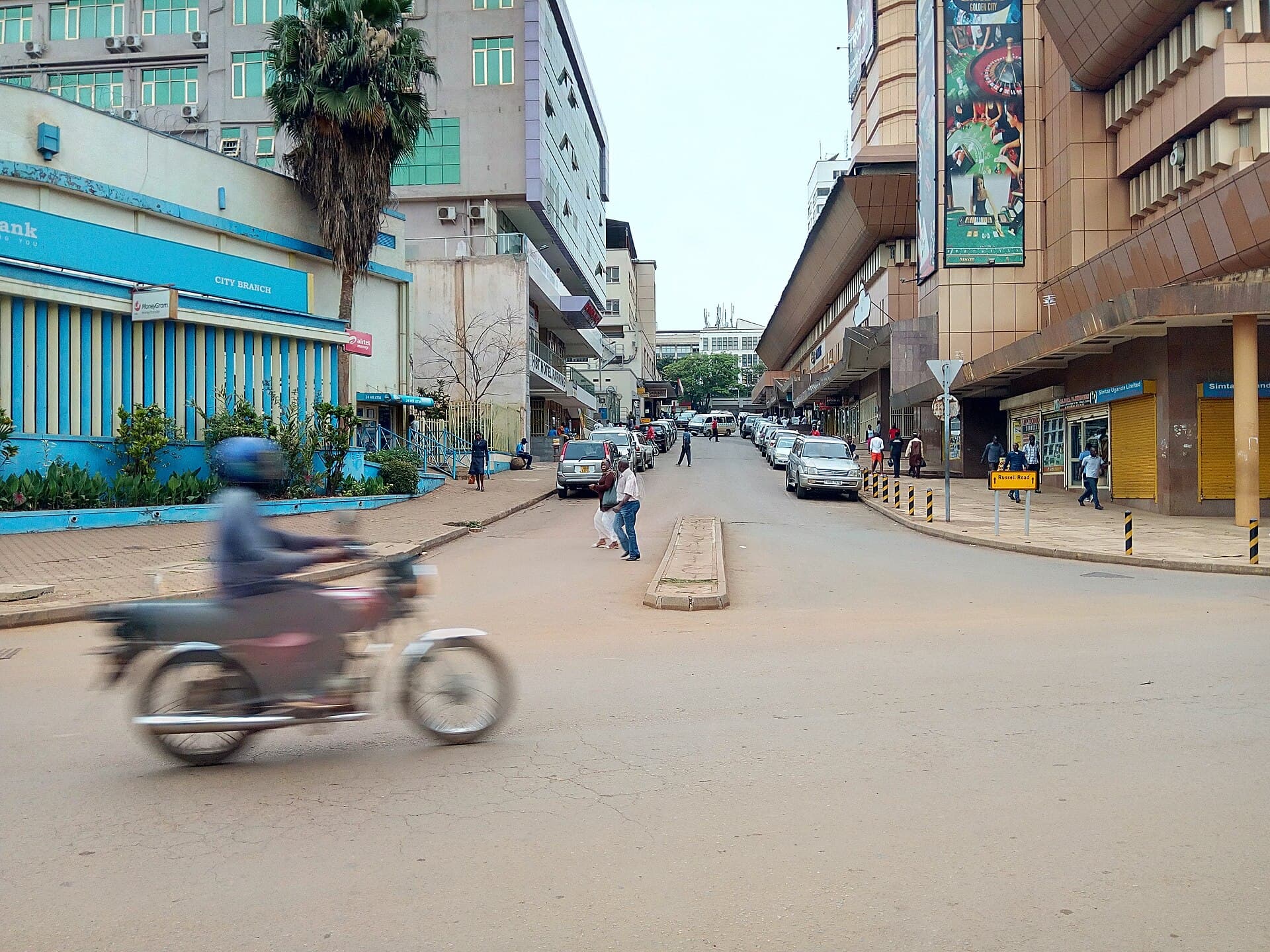 A boda boda motorcycle moving fast on a Ugandan road